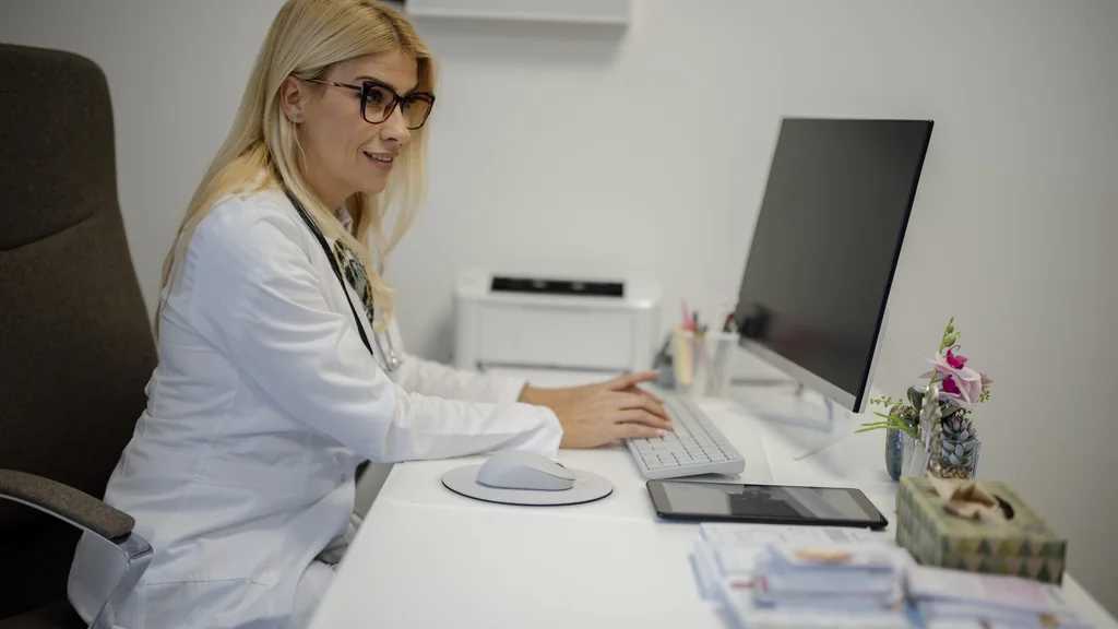 Medico seduto alla scrivania mentre usa un computer in un ambulatorio